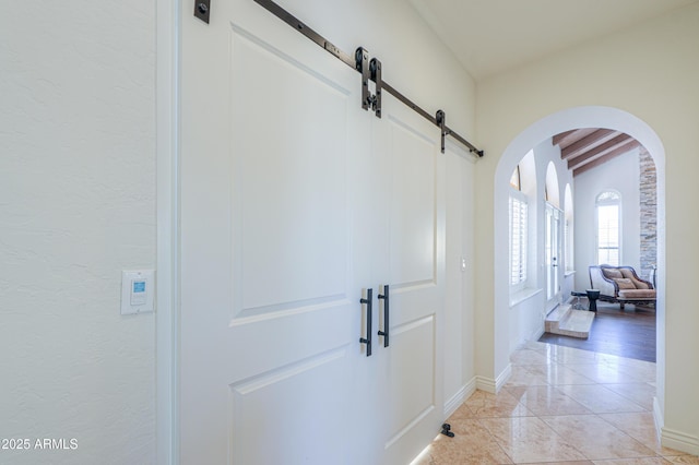 corridor with light tile patterned flooring, a barn door, and vaulted ceiling with beams