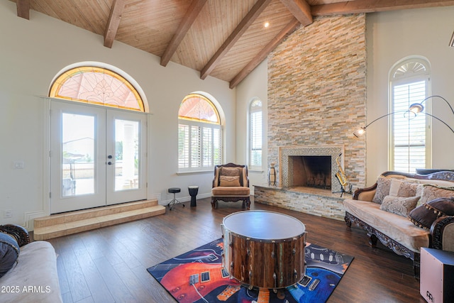 living room featuring high vaulted ceiling, dark hardwood / wood-style floors, a stone fireplace, and beamed ceiling