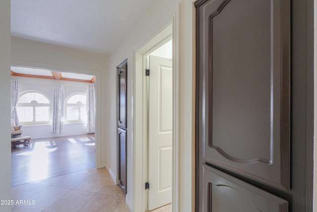 corridor with light tile patterned floors and a textured ceiling