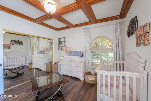 bedroom with beam ceiling, a nursery area, dark hardwood / wood-style floors, and coffered ceiling