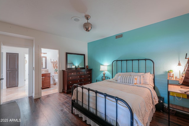 bedroom with ensuite bathroom and dark hardwood / wood-style flooring