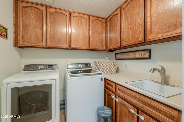 laundry room with washer and dryer, sink, a textured ceiling, and cabinets