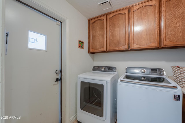 washroom with washer and dryer and cabinets