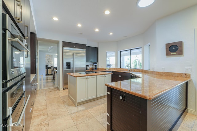 kitchen featuring white cabinetry, kitchen peninsula, stainless steel appliances, and wood counters