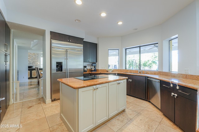 kitchen featuring light tile patterned floors, appliances with stainless steel finishes, sink, and a center island