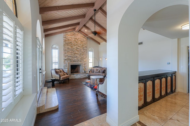 living room with a stone fireplace, wooden ceiling, light wood-type flooring, high vaulted ceiling, and beam ceiling