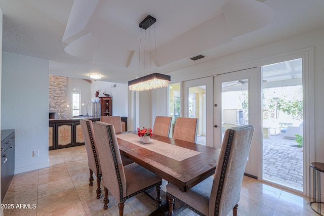 tiled dining area featuring french doors and a tray ceiling