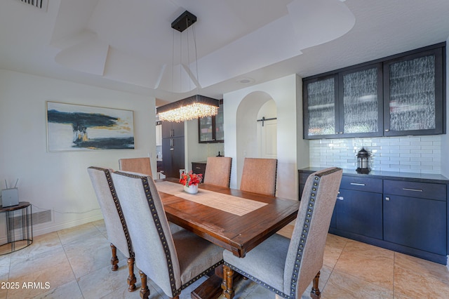 tiled dining room featuring a tray ceiling and an inviting chandelier