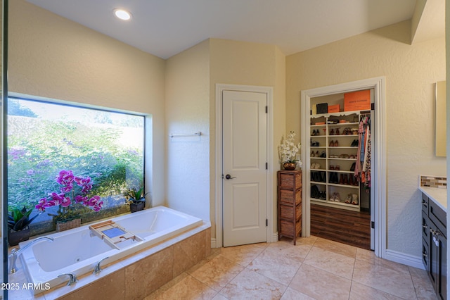 bathroom featuring tile patterned floors, a relaxing tiled tub, and vanity