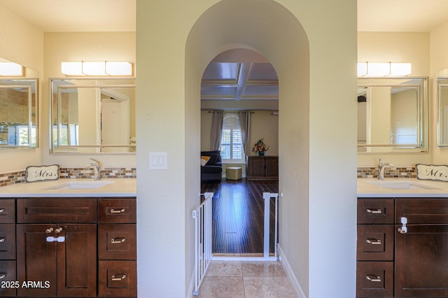 bathroom featuring coffered ceiling, backsplash, vanity, and beamed ceiling