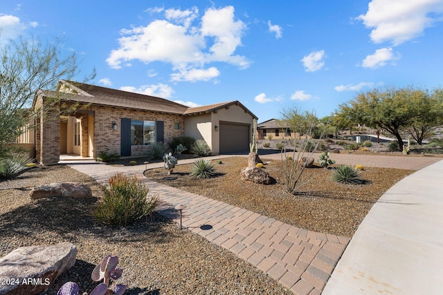 view of front of home featuring brick siding, an attached garage, and driveway