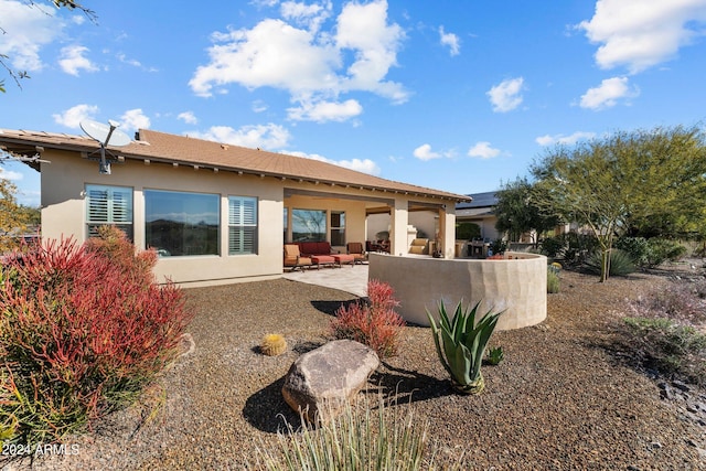 rear view of house featuring a patio, an outdoor hangout area, and stucco siding