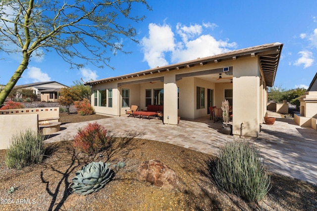 back of house with stucco siding, a ceiling fan, and a patio area