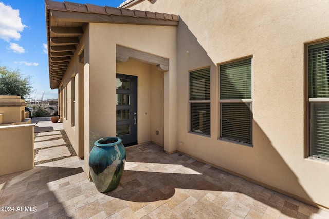 view of exterior entry with stucco siding, a tiled roof, and a patio