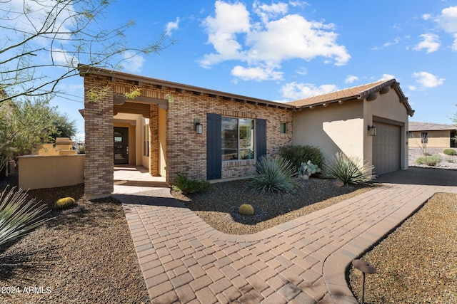 view of front of house with brick siding, stucco siding, driveway, and a garage