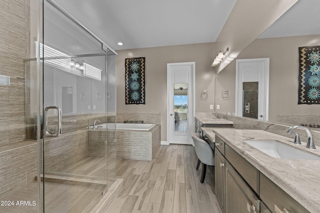 full bathroom with two vanities, a stall shower, a sink, wood finished floors, and a bath