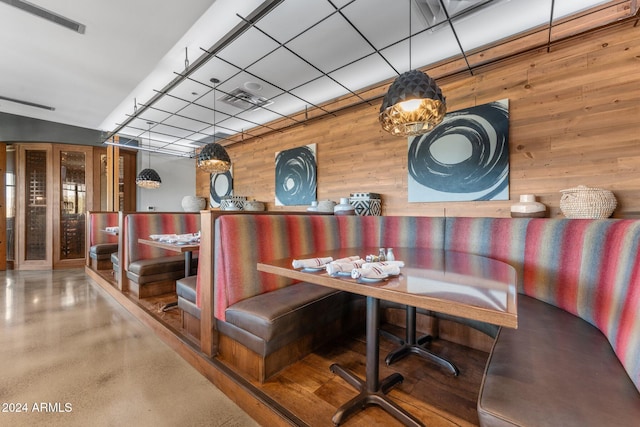 interior space with a drop ceiling and wooden walls