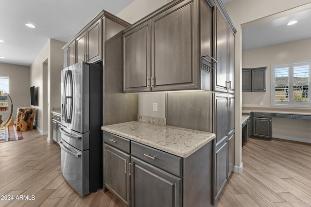 kitchen with light hardwood / wood-style flooring, light stone countertops, dark brown cabinetry, and stainless steel refrigerator