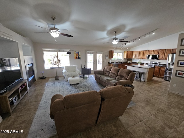 living room featuring vaulted ceiling, track lighting, tile patterned floors, and ceiling fan