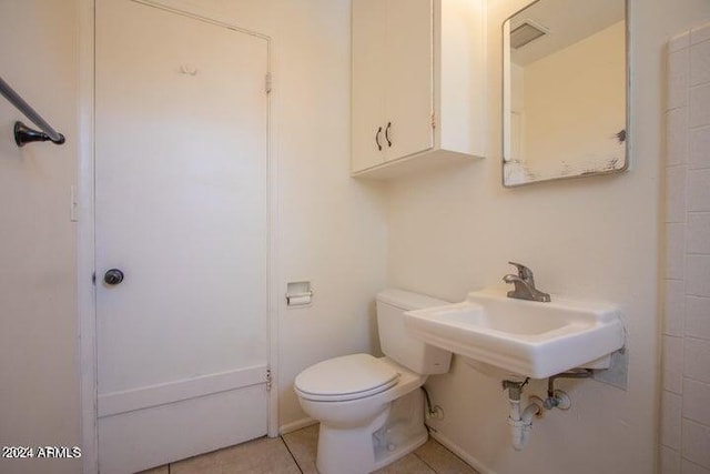 bathroom featuring toilet, tile flooring, and sink