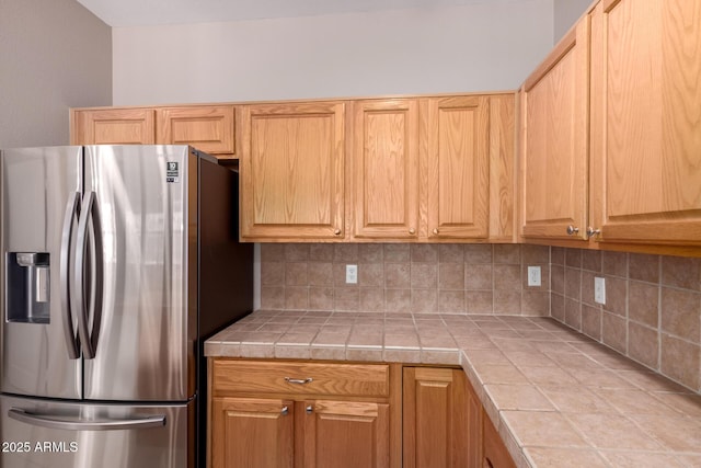 kitchen with tile countertops, tasteful backsplash, and stainless steel fridge with ice dispenser