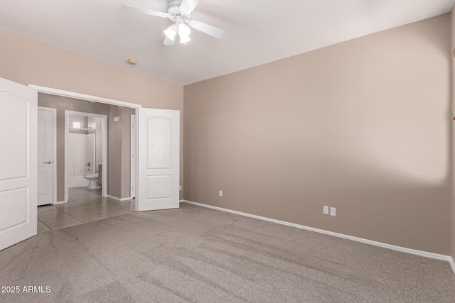 unfurnished bedroom with baseboards, a ceiling fan, ensuite bath, carpet, and tile patterned flooring