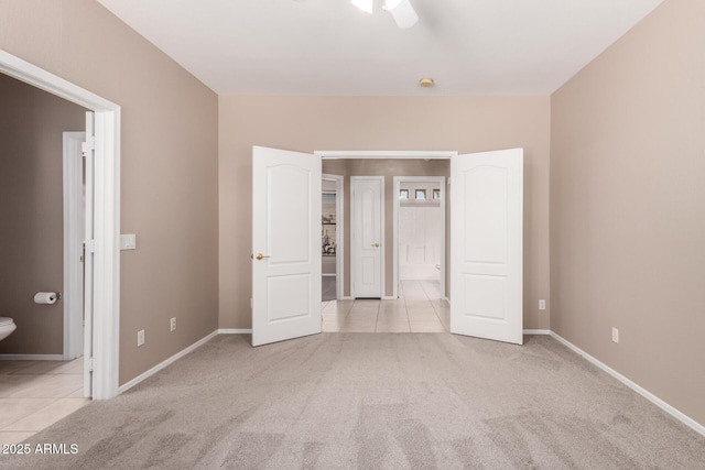 unfurnished bedroom featuring light carpet, light tile patterned floors, baseboards, and connected bathroom