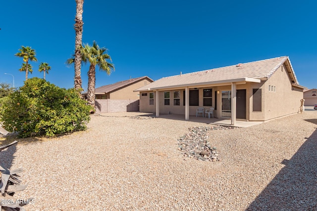 back of property featuring stucco siding, a patio, a tiled roof, and fence