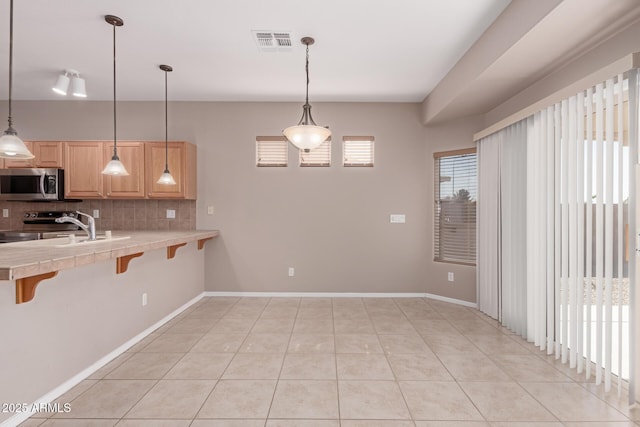 kitchen featuring light tile patterned floors, tasteful backsplash, visible vents, stainless steel appliances, and a kitchen bar