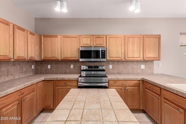 kitchen with stainless steel appliances, tile counters, and decorative backsplash