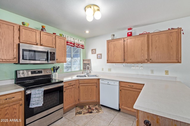 kitchen featuring stainless steel appliances, light countertops, a sink, and light tile patterned flooring