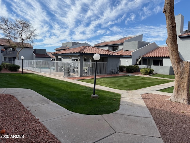 back of house featuring a yard, a tile roof, fence, and stucco siding