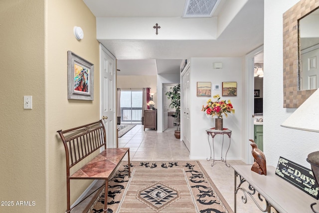 hallway with light tile patterned floors, visible vents, and baseboards