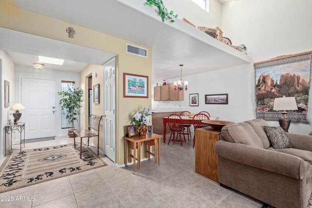 living area featuring light tile patterned floors, visible vents, and a chandelier