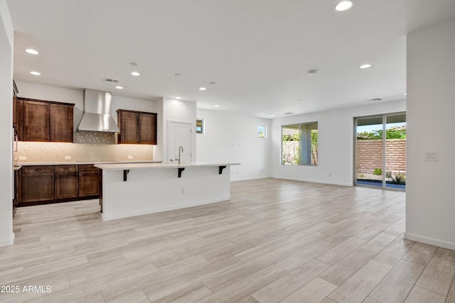 4515 Charro Ct, Wickenburg, AZ 85390 - kitchen featuring wall chimney range hood, recessed lighting, an island with sink, open floor plan, and decorative backsplash