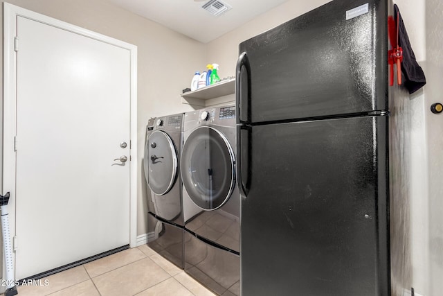 laundry room with light tile patterned floors, visible vents, washer and dryer, and laundry area
