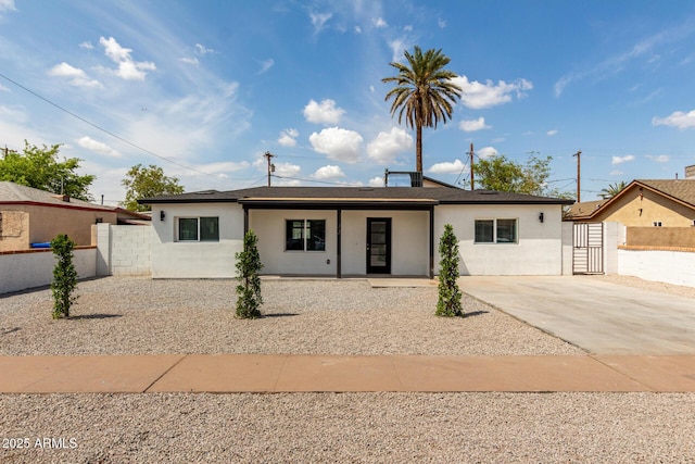 ranch-style house featuring concrete driveway, stucco siding, and fence