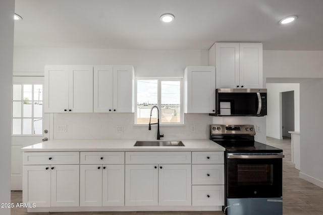 kitchen featuring a wealth of natural light, stainless steel appliances, white cabinets, and a sink