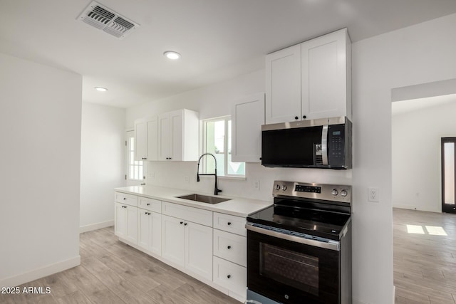 kitchen with light wood-style floors, visible vents, appliances with stainless steel finishes, and a sink