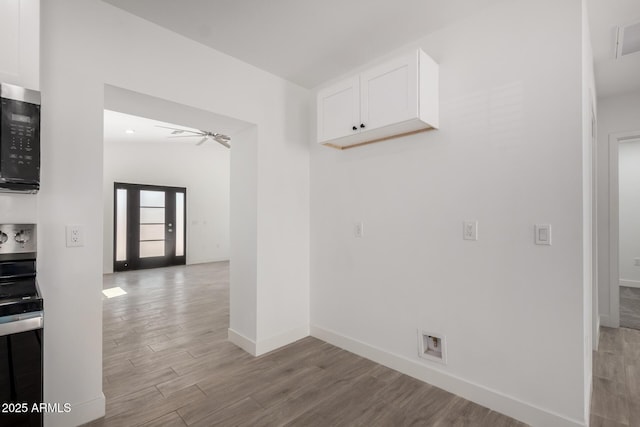 interior space with baseboards, light wood finished floors, and a ceiling fan