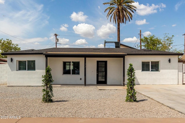 ranch-style house featuring covered porch, stucco siding, and roof with shingles