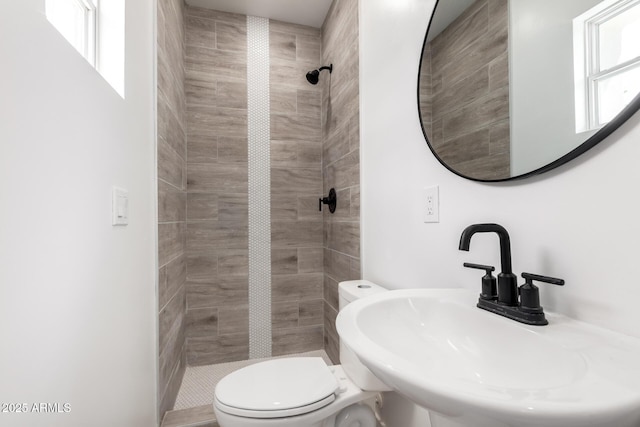 full bathroom featuring a sink, toilet, and tiled shower