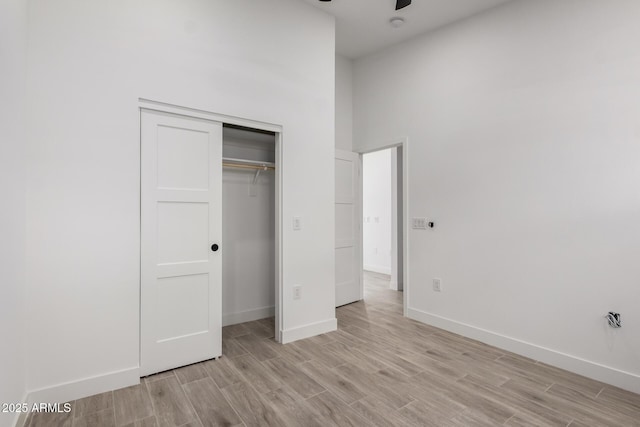 unfurnished bedroom featuring a closet, light wood-type flooring, and baseboards
