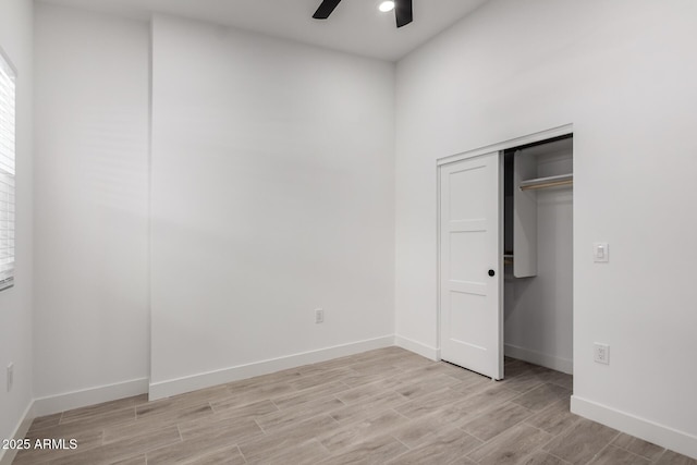 unfurnished bedroom with light wood-style flooring, baseboards, a ceiling fan, and a closet