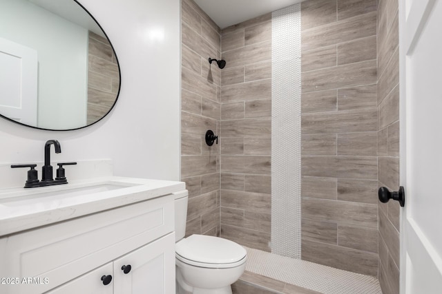 bathroom featuring vanity, toilet, and a tile shower