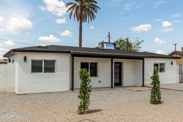 rear view of house featuring stucco siding, a shingled roof, fence, and a patio