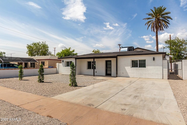 ranch-style house with a gate, fence, stucco siding, and concrete driveway