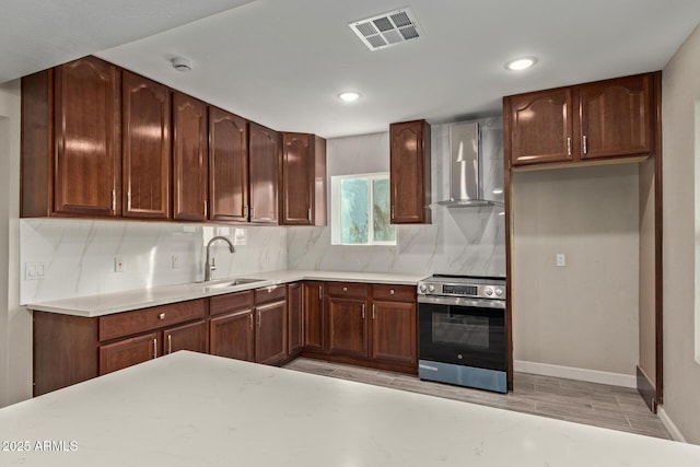 kitchen featuring electric stove, sink, backsplash, and wall chimney exhaust hood