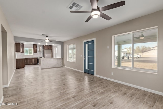 unfurnished living room with ceiling fan, light hardwood / wood-style floors, and sink