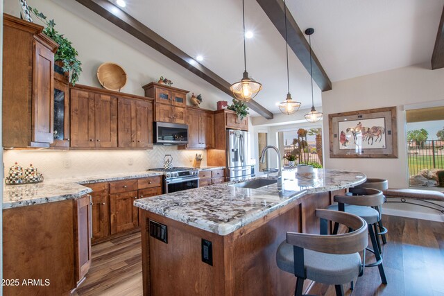 3441 N 162nd Ln, Goodyear, AZ 85395 - kitchen featuring appliances with stainless steel finishes, brown cabinets, a sink, decorative backsplash, and a breakfast bar area